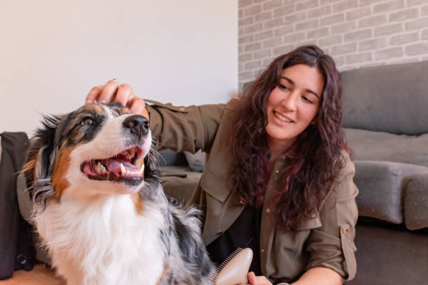 Young woman on the ground smiling while petting her dog.