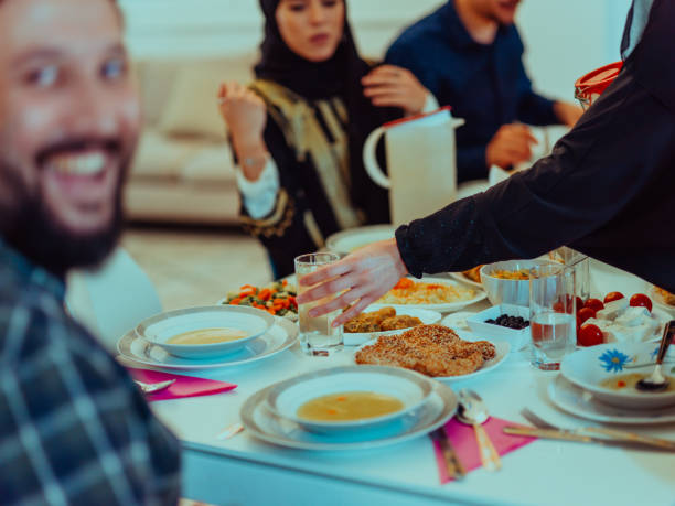 istock Eid Mubarak Muslim family having Iftar dinner taking pictures with smartphone while eating traditional food during Ramadan feasting month at home. The Islamic Halal Eating and Drinking Islamic family 1483577432