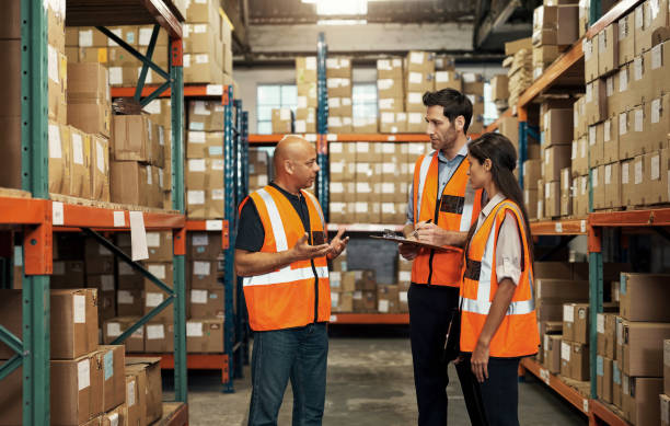 istock Warehouse, teamwork and employees talking with checklist for shipping, distribution or inventory. Collaboration, group and people, engineers or workers discuss stock of boxes, logistics or storage. 1483579528