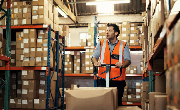istock Warehouse, boxes and man with pallet truck for stock, inventory or distribution. Thinking, worker and person with forklift trolley for logistics, storage or package for shipping, cargo or freight. 1483579752