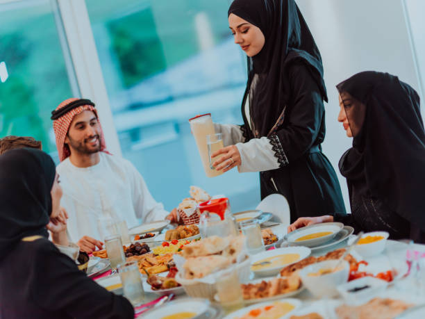 istock Eid Mubarak Muslim family having Iftar dinner drinking water to break feast. Eating traditional food during Ramadan feasting month at home. The Islamic Halal Eating and Drinking 1483580613
