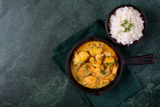 Fish curry with codfish, pollack and shrimps with coconut milk served in cast iron pan