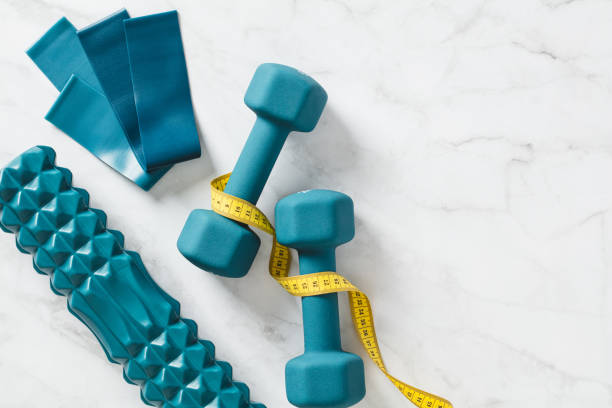 istock Flat lay dumbbells, measure tape, roller, elastic band on marble background. Weight loss, workout training concept. 1483586176