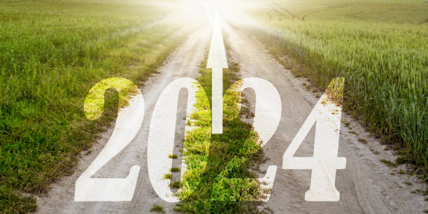 istock Bright sun rays lighting in end of long sandy road with 2024 inscription 1483587931