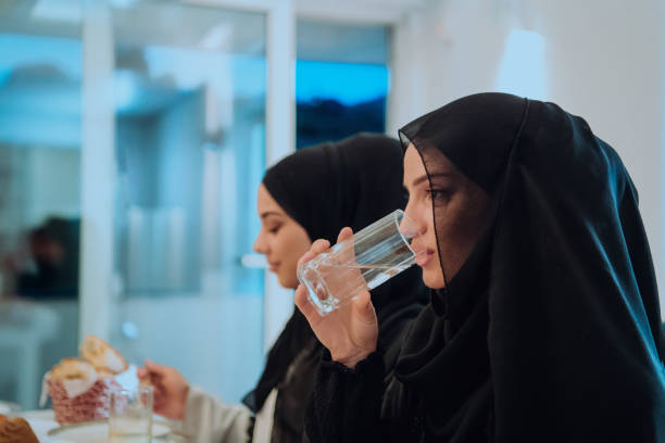 istock Eid Mubarak Muslim family having Iftar dinner drinking water to break feast. Eating traditional food during Ramadan feasting month at home. The Islamic Halal Eating and Drinking at modern western Isla 1483591446