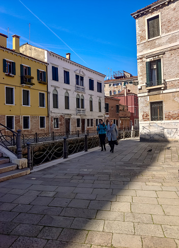 Venice, Italy - April 2023.People walking near the venecian canal with the neclassic building in one side in a sunny day