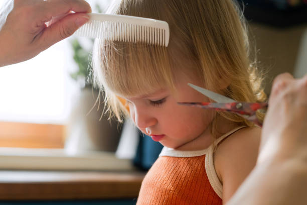 Mother cutting hair of her little girl