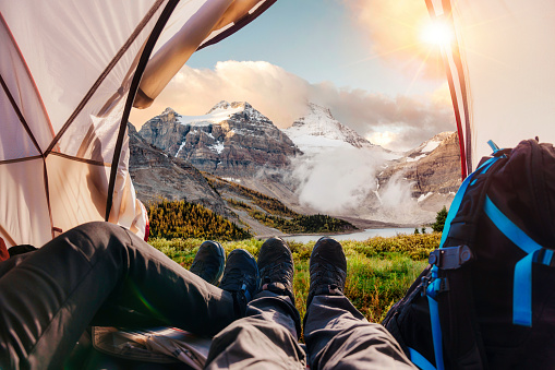 Legs of couple hiker relaxing inside a tent with Rocky Mountains view in national park at BC, Canada