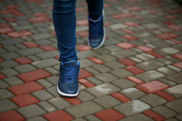 Blue leather sneakers with a white sole and blue laces on the legs of a girl on a paving slab Blue leather sneakers with a white sole and blue laces on the legs of a girl on a paving slab womens blue suede shoes stock pictures, royalty-free photos & images