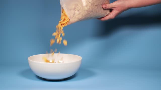 Female hand pouring cornflakes from a white plastic bag into a bowl