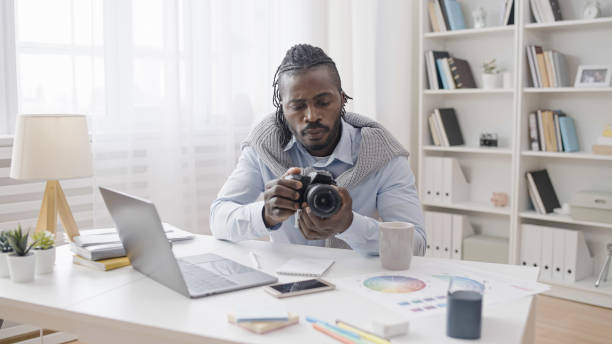 istock A male artist is adjusting his new professional photo camera and watching a tutorial on his laptop 1483612530