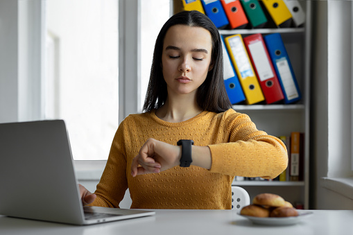 Woman looking at her watch at her workplace in office