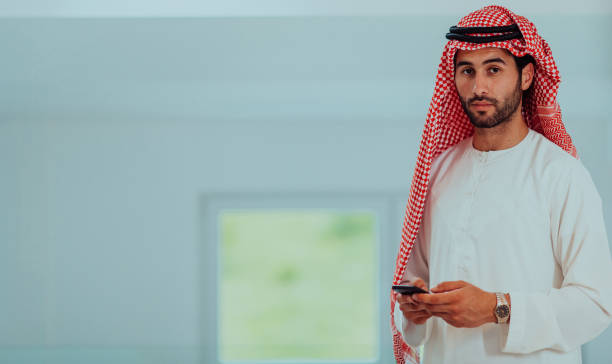 istock Young modern Muslim Arabian businessmen wearing traditional clothes while using smartphones at home. 1483621037