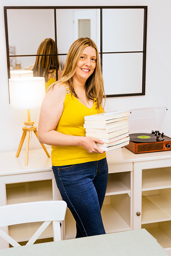 Portrait of woman with a yellow shirt and a lot of book in her hands