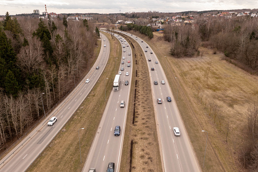Drone photography of major highway in a city and traffic during springtime day. High angle view.