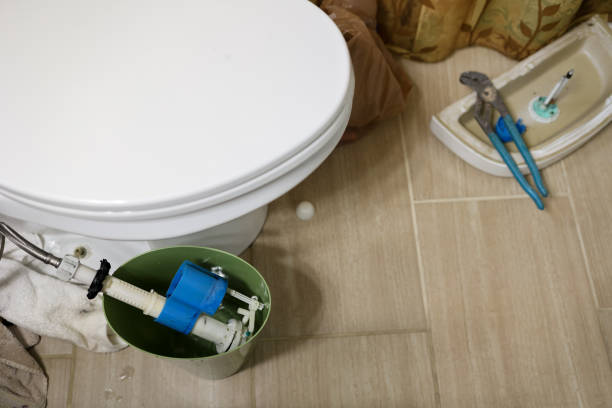 A leaking toilet pipe in a residential bathroom being repaired