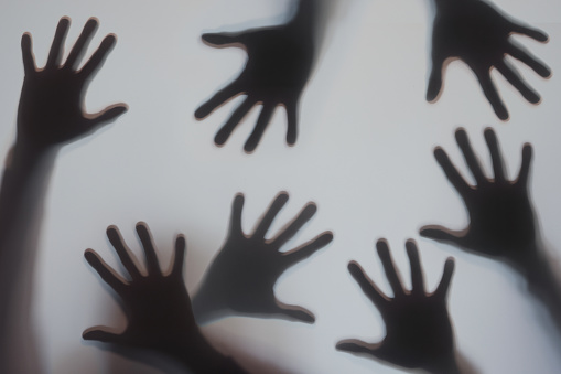 Human hands silhouette behind frosted glass