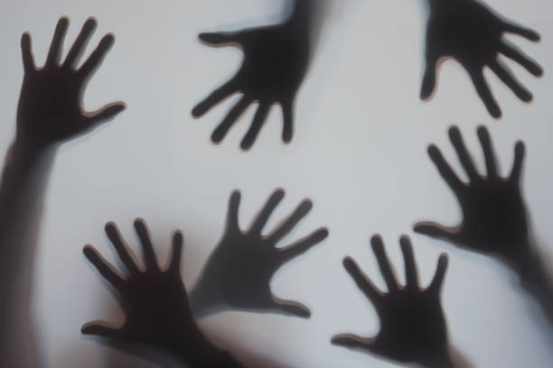 Human hands silhouette behind frosted glass stock photo