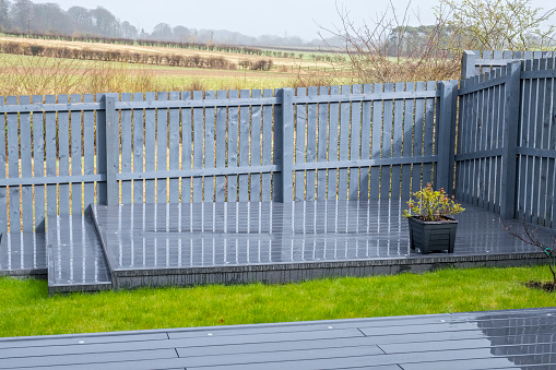 Ash grey composite decking on two levels on a rainy wet day