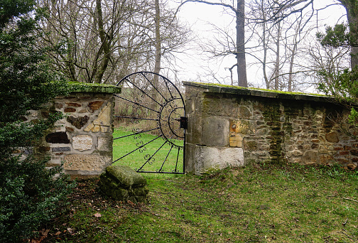 an ornate iron gate along an old stone wall on the grounds of an abandoned estate in the countryside outside Dresden,  Germany