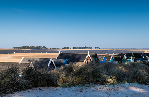 View overlooking beach hut roof tops to the vast sandy beach at Wells Next The Sea, North Norfolk, England UK.