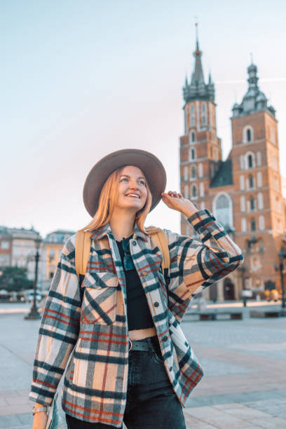매력적인 젊은 여성 관광객이 새로운 도시를 탐험하고 있다. 모자를 쓴 소녀가 크라쿠프의 시장 광장에서 종이 지도를 들고 있다. - polish culture poland malopolskie province cathedral 뉴스 사진 이미지