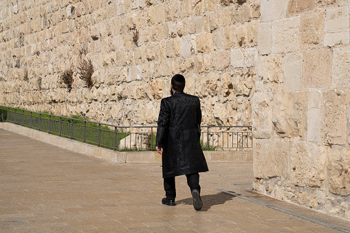 Jerusalem, Israel - November 12th, 2022: An  ultra orthodox jewish man on a saturday morning, walking by the old city wall of Jerusalem, Israel.