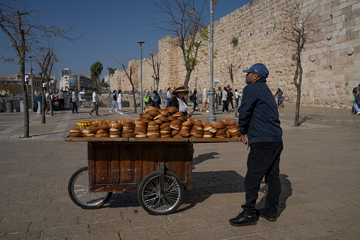 Jerusalem, Israel - November 12th, 2022: A pastry vendor next to his cart, waiting for customers by the old city wall of Jerusalem, Israel.