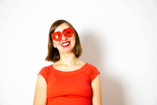 A smiling young girl in a red sunglasses and a red shirt. Valentines day. High quality photo