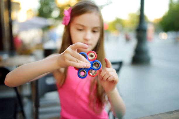 istock Cute school girl playing with colorful fidget spinner 1483644222