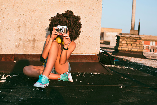 Portrait of a teenage girl on a rooftop. Тaking photos with an analog camera. Enjoying the sunset.