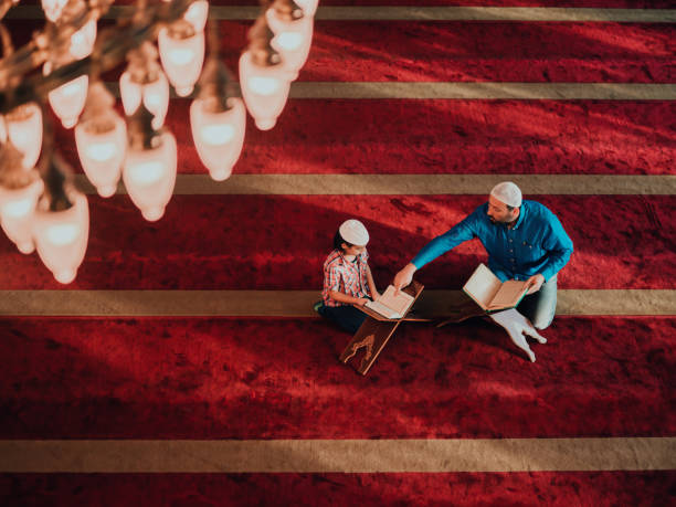 Muslim prayer father and son in mosque praying and reading holly book Quran together islamic education concept Muslim prayer father and son in mosque praying and reading holly book Quran together islamic education concept. father allah stock pictures, royalty-free photos & images