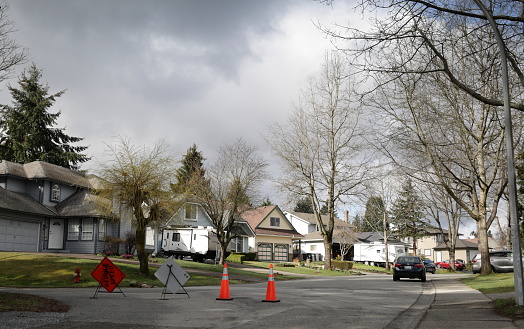 Traffic cones and road signs alert neighbours about road repairs in the Fleetwood-Tynehead neighbourhood of Surrey. Cloudy afternoon in Metro Vancouver.