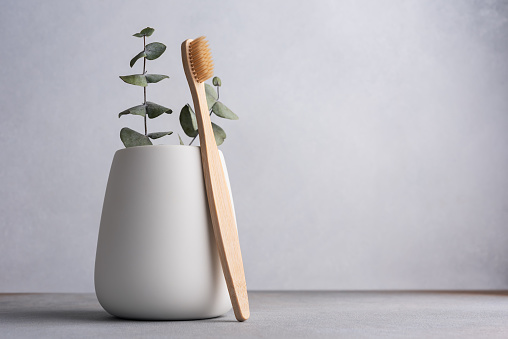 Natural eco friendly toothbrush with wooden bamboo handle in a white toothbrush holder. Zero waste lifestyle.