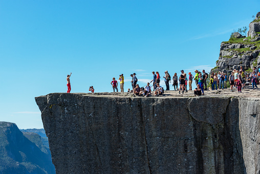 Preikestolen, Stavanger, Norway - July 17, 2022: Posing and queuing for an exciting picture on the famous Preikestolen (Pulpit Rock) over the Lysefjord.