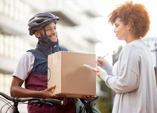 istock Black man, box and tablet in delivery service, package or parcel for female customer order in city. Happy African American male courier employee delivering cargo to woman with touchscreen signature 1483654932