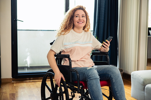 Portrait of a young woman enjoying at home and using her smartphone