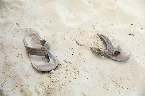 sandals resting in the soft beach sand evoke the feelings of relaxation, freedom, and adventure associated with a beach vacation. They represent the carefree beach lifestyle and the simple pleasures