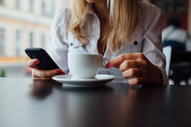 istock Woman in cafe using mobile phone and drinking coffee 1483668677