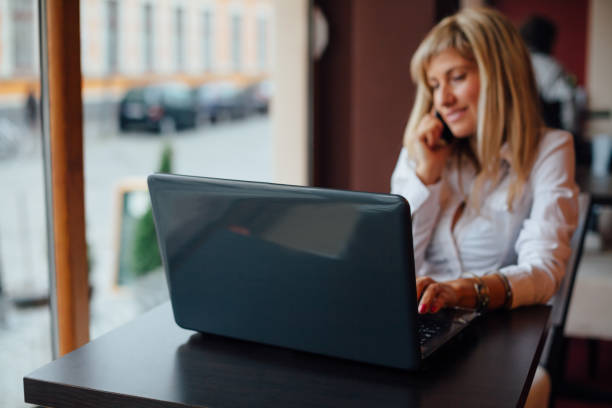 istock Woman using laptop and mobile phone at the same time in a cafe 1483668705