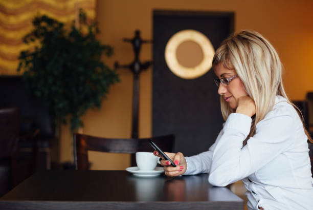 istock Side view of woman using new smart phone in a cafe 1483668712