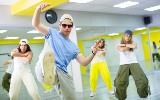 istock Confident sporty teens moving their foot right into camera while exercising dance together in hall 1483674930
