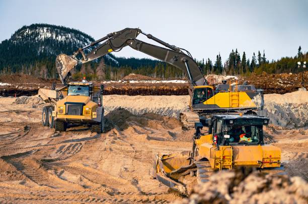 istock Excavator loading a dump truck with topsoil and with an approaching bulldozer 1483675979