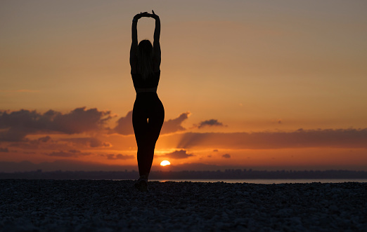 Young beautiful woman practicing on the beach at sunrise, Antalya, Turkiye