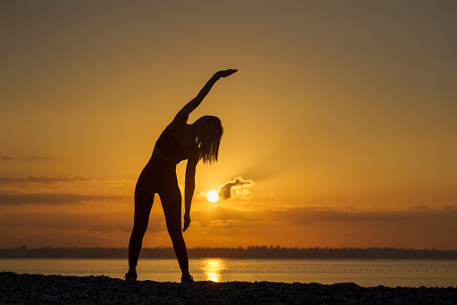 Young beautiful woman practicing on the beach at sunrise, Antalya, Turkiye