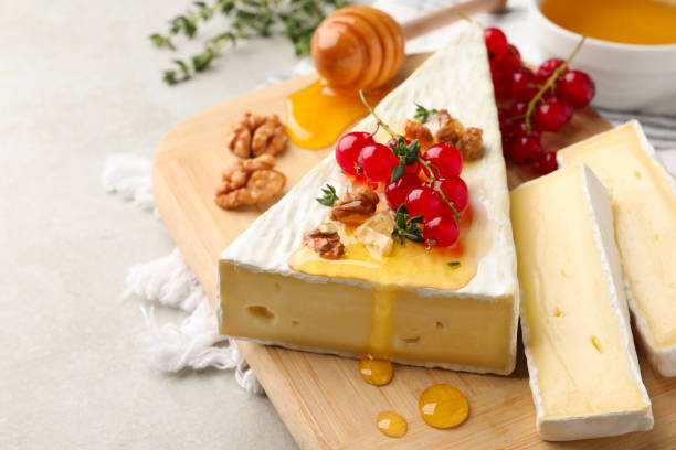 istock Brie cheese served with red currants, walnuts and honey on light table, closeup 1483692606
