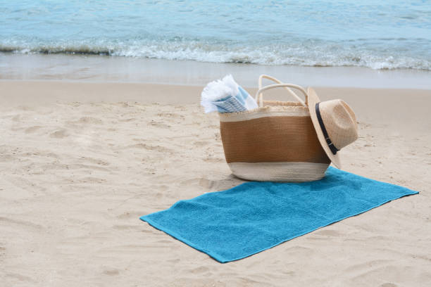 istock Bag with blanket, beach towel and straw hat on sandy seashore, space for text 1483694176