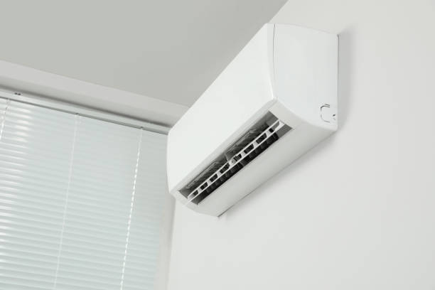 Modern air conditioner on white wall indoors, low angle view