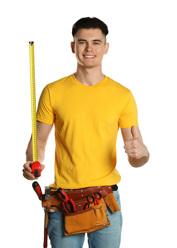 Handyman with measuring tape and tool belt showing thumb up isolated on white