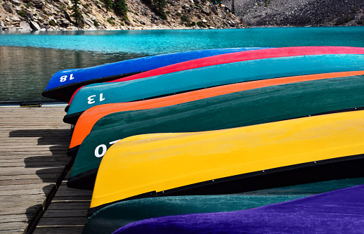 Bright and colorful canoes storred upside down on wooden dock at Lake Moraine in Banff Alberta